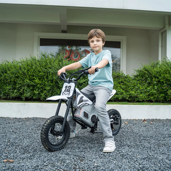 Young boy sitting on a white and black kids electric dirt bike with number 12